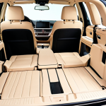 An interior shot of a BMW X5, showcasing its intelligent 2nd-row seat folding strategy. The 40:20:40 split-fold seats are configured to accommodate both long items like skis or fishing rods through the middle section, while a child's car seat or stroller remains on one side, highlighting flexible space for family and bulky gear. The setting emphasizes practical luxury and ingenious design.